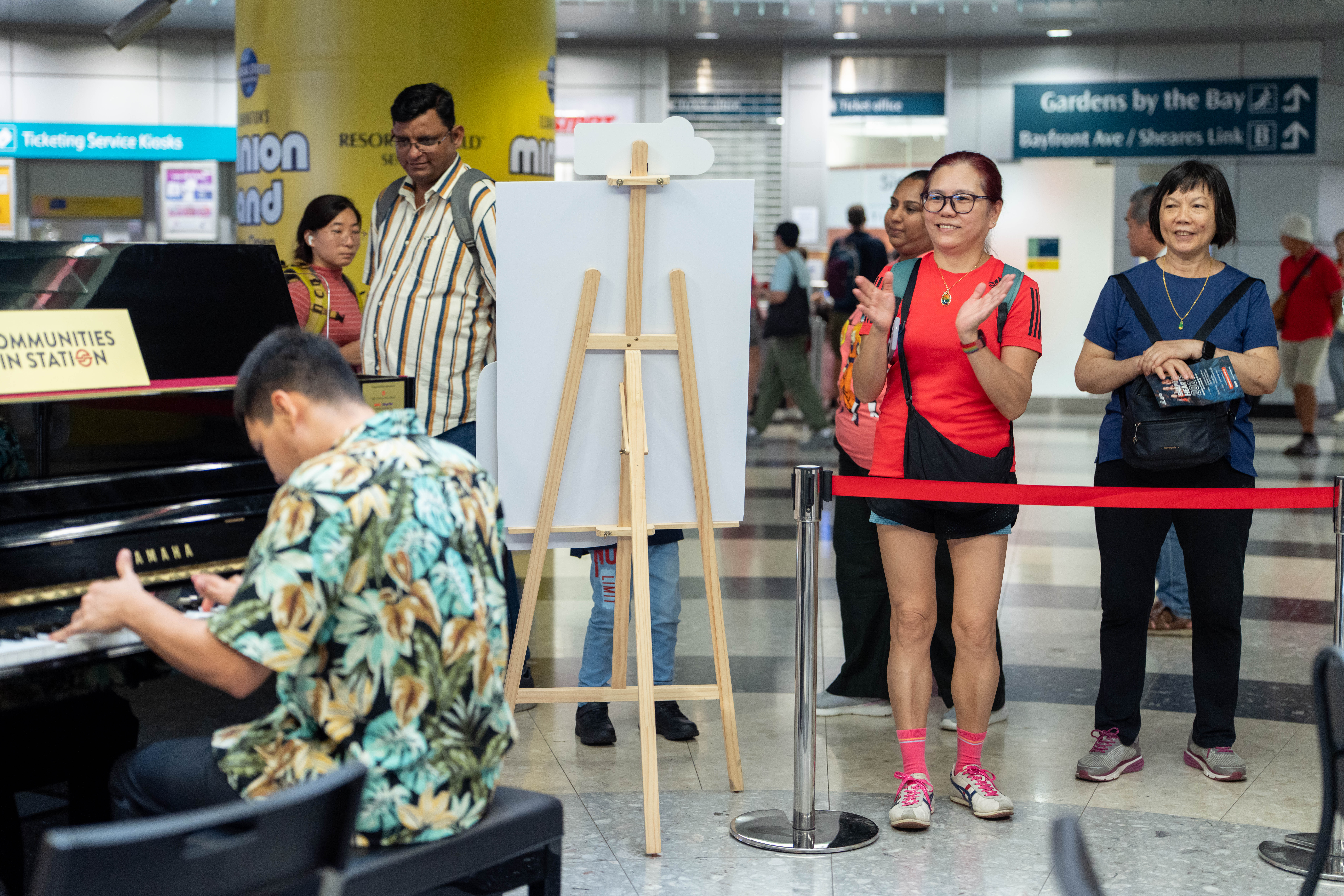 Audience applauding a person with disabilities performing live on a piano.
